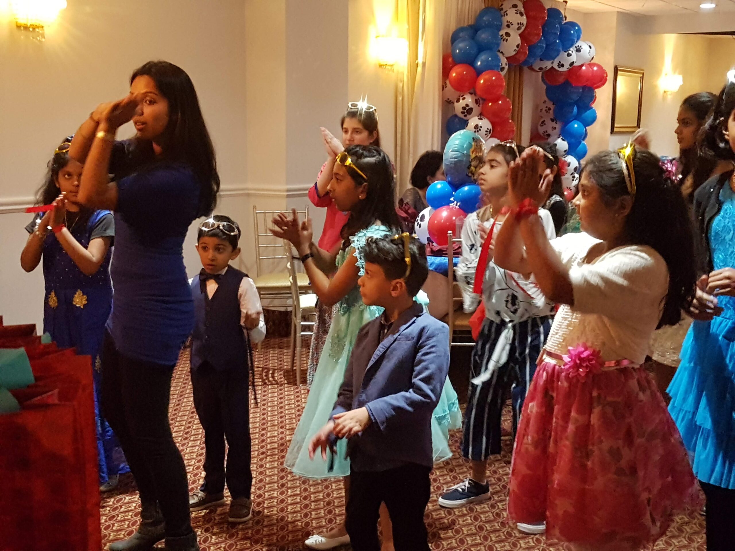 Dance Expression students practicing dance moves at a birthday party, set in a festive room decorated with balloons.